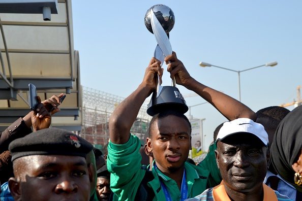 Nigeria's Kelechi Nwakali carries the Fifa Under-17 World Cup trophy on his head in the midst of a crowd gathered to receive the triumphant Nigeria U17 team, the Golden Eaglets, at Nnamdi Azikiwe Airport in Abuja, on November 11, 2015. Nigeria's Golden Eaglets emerged champions of the Fifa Under-17 World Cup in Chile after defeating Mali 2-0. AFP PHOTO / STRINGER        (Photo credit should read -/AFP/Getty Images)