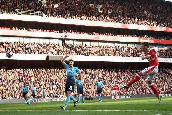 Arsenal's German midfielder Mesut Ozil (R) shoot to score their third goal during the English Premier League football match between Arsenal and Swansea City at the Emirates Stadium in London on October 15, 2016. / AFP / Justin TALLIS / RESTRICTED TO EDITORIAL USE. No use with unauthorized audio, video, data, fixture lists, club/league logos or 'live' services. Online in-match use limited to 75 images, no video emulation. No use in betting, games or single club/league/player publications. / (Photo credit should read JUSTIN TALLIS/AFP/Getty Images)