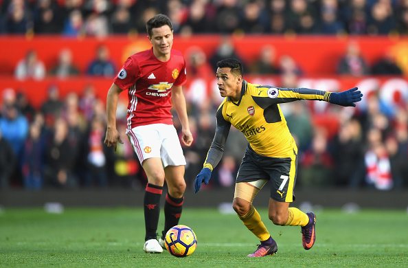 MANCHESTER, ENGLAND - NOVEMBER 19: Alexis Sanchez of Arsenal (R) takes the ball past Ander Herrera of Manchester United (L) during the Premier League match between Manchester United and Arsenal at Old Trafford on November 19, 2016 in Manchester, England.