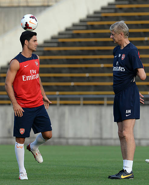 Arsenal midfielder Mikel Arteta (L) chats with head coach Arsene Wenger (R) during their training session in Nagoya on July 21, 2013. (TOSHIFUMI KITAMURA/AFP/Getty Images)