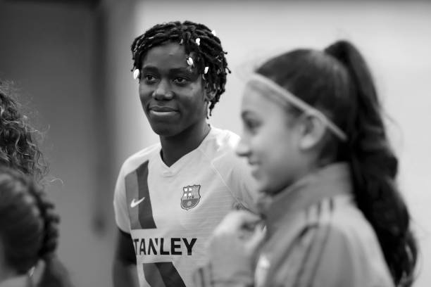 BOREHAMWOOD, ENGLAND - AUGUST 14: (EDITORS NOTE: Image has been converted to black and white.) Asisat Oshoala of Barcelona speaks to a match day mascot ahead of the Pre Season Friendly match between Arsenal and Barcelona at Meadow Park on August 14, 2019 in Borehamwood, England. (Photo by Naomi Baker/Getty Images)