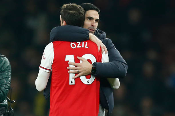 Arsenal's Spanish head coach Mikel Arteta (R) embraces Arsenal's German midfielder Mesut Ozil (L) on the pitch after the English Premier League football match between Arsenal and Manchester United at the Emirates Stadium in London on January 1, 2020. - Arsenal won the game 2-0. (Photo by Ian KINGTON / IKIMAGES / AFP)