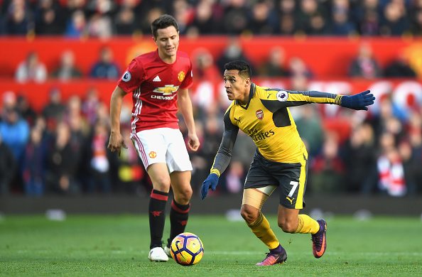 MANCHESTER, ENGLAND - NOVEMBER 19: Alexis Sanchez of Arsenal (R) takes the ball past Ander Herrera of Manchester United (L) during the Premier League match between Manchester United and Arsenal at Old Trafford on November 19, 2016 in Manchester, England.
