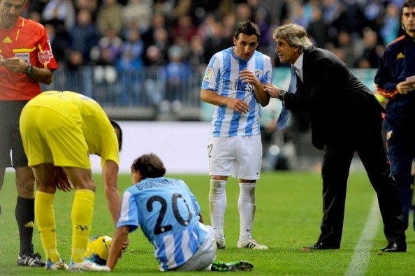 Malaga's Chilean coach Manuel Pellegrini (R) talks with midfielder Santiago Cazorla (2R) during the Spanish league football match Malaga CF vs Villarreal on November 28, 2011 at Rosaleda stadium in Malaga. AFP PHOTO/ JORGE GUERRERO (Photo credit should read Jorge Guerrero/AFP/Getty Images)