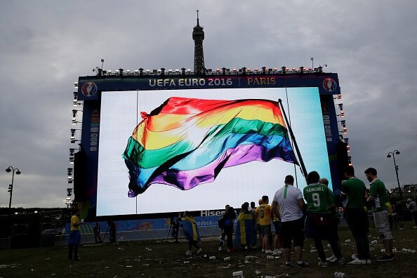 Supporters stand in front of a giant screen displaying a rainbow flag to pay tribute to the victims of the shooting of Orlando, in a fan zone in Pa...