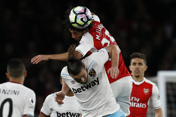 Arsenal's Egyptian midfielder Mohamed Elneny (up) wins a header from West Ham United's English striker Andy Carroll during the English Premier Leag...