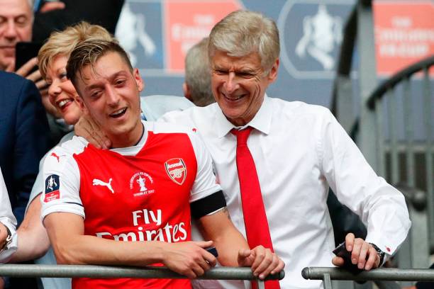 Arsenal's French manager Arsene Wenger (R) and Arsenal's German midfielder Mesut Ozil smile as Arsenal players celebrate their victory over Chelsea...