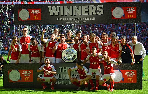 Arsenal's French manager Arsene Wenger (R) and his players celebrate with the trophy after beating Chelsea in the FA Community Shield football matc...