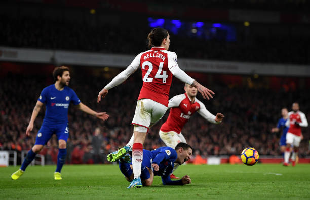 Eden Hazard of Chelsea lies on the ground holding his ankle after being touched lightly on the sole of his foot by Hector Bellerin which leads to C...