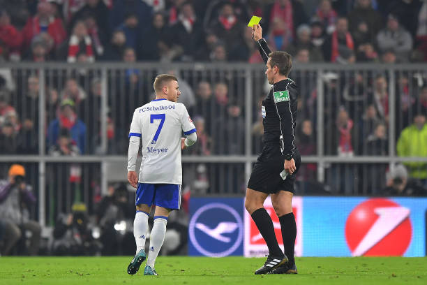 MUNICH, GERMANY - FEBRUARY 10: Maximilian Meyer of Schalke (l) is shown a yellow card by referee Tobias Stieler during the Bundesliga match between FC Bayern Muenchen and FC Schalke 04 at Allianz Arena on February 10, 2018 in Munich, Germany. (Photo by Sebastian Widmann/Bongarts/Getty Images)