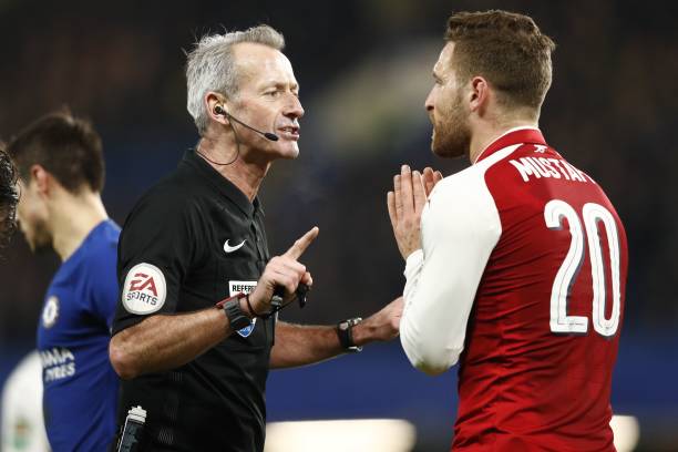 English referee Martin Atkinson (L) speaks with Arsenal's German defender Shkodran Mustafi during the English League Cup semi-final first leg football match between Chelsea and Arsenal at Stamford Bridge in London on January 10, 2018. / AFP PHOTO / Adrian DENNIS /