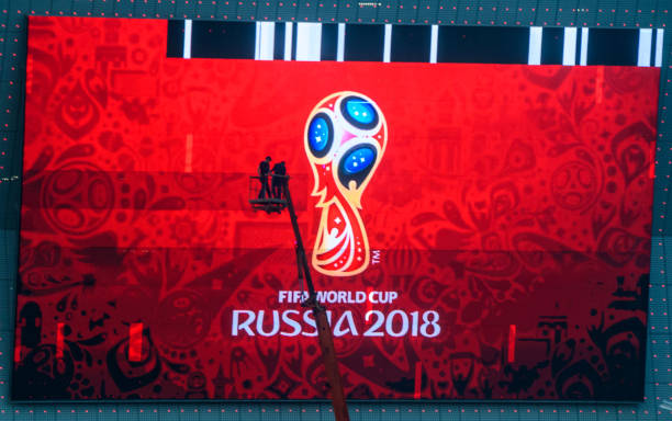 TOPSHOT - Workers fix a giant screen featuring the Russian FIFA World Cup logo, mounted outside Rostov Arena in the southern Russian city of Rostov...