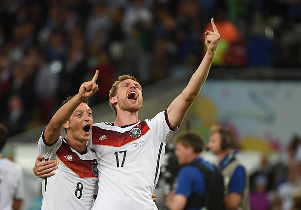 Germany's midfielder Mesut Ozil (L) and Germany's defender Per Mertesacker celebrate after their team won the 2014 FIFA World Cup final football ma...