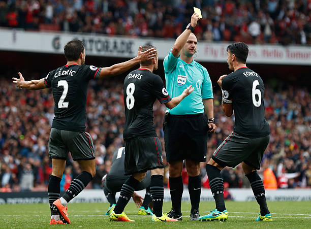 LONDON, ENGLAND - SEPTEMBER 10: Bobby Madley (C) gives Jose Fonte of Southampton a yellow card for a foul in the box during the Premier League matc...