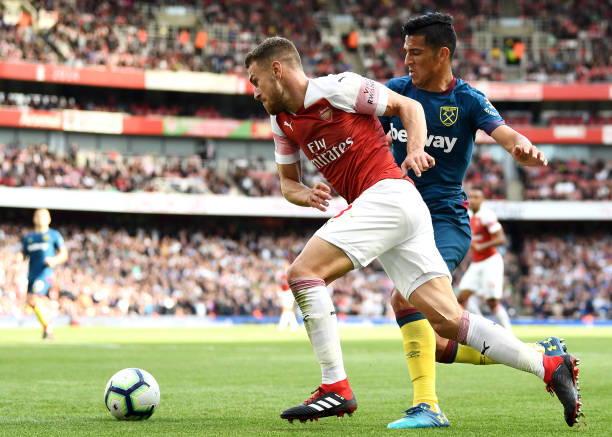 LONDON, ENGLAND - AUGUST 25: Aaron Ramsey of Arsenal is challenged by Lucas Perez of West Ham United during the Premier League match between Arsena...