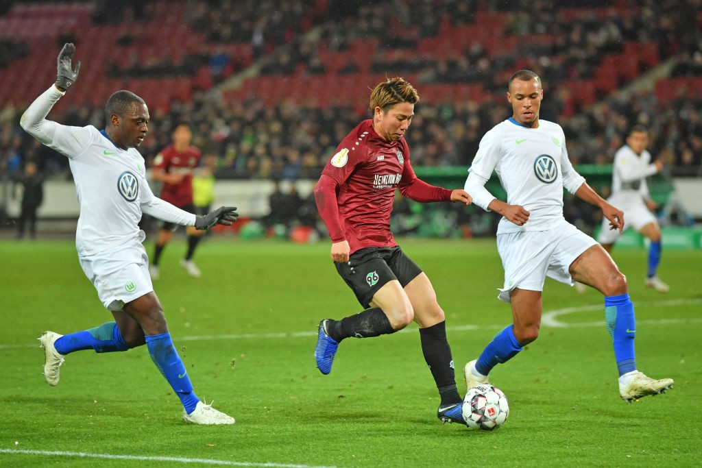 HANOVER, GERMANY - OCTOBER 30: Jerome Roussillon (L) and John Anthony Brooks of Wolfsburg tackle Takuma Asano (C) of Hannover during the DFB Cup ma...