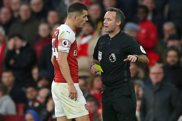 English referee Paul Tierney shows a yellow card to Arsenal's Swiss midfielder Granit Xhaka (L) during the English Premier League football match between Arsenal and Huddersfield Town at the Emirates Stadium in London on December 8, 2018. (Photo by Daniel LEAL-OLIVAS / AFP)