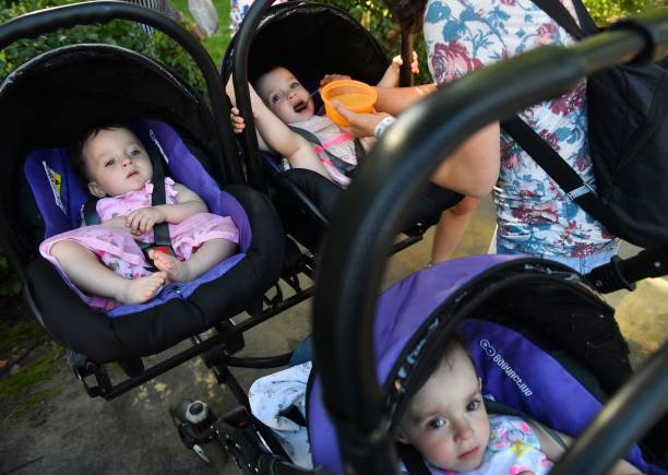 A mother feeds her triplets as they attend the children's Festival Of Twins, in Kiev, on August 11, 2018. - Representatives of the Ukrainian Records Book set the new country's record at more than 200 pairs of twins and triplets during the event. (Photo by Sergei SUPINSKY / AFP) 