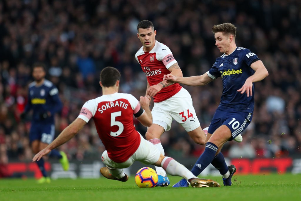 LONDON, ENGLAND - JANUARY 01: Tom Cairney of Fulham shoots while under pressure from Sokratis Papastathopoulos of Arsenal and Granit Xhaka of Arsen...