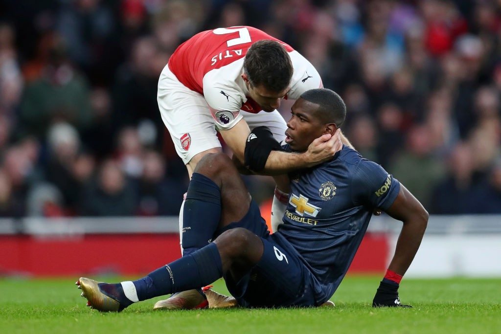 LONDON, ENGLAND - MARCH 10: Paul Pogba of Manchester United is helped up by Sokratis Papastathopoulos of Arsenal during the Premier League match between Arsenal FC and Manchester United at Emirates Stadium on March 10, 2019 in London, United Kingdom. (Photo by Catherine Ivill/Getty Images)