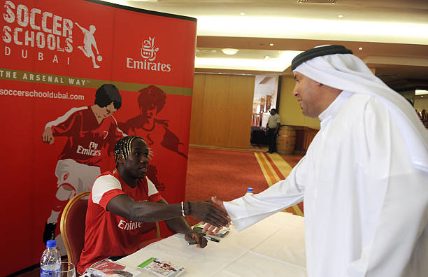 Arsenal's French defender Bacary Sagna shakes hands with an unidentified Emirati man during his visit to the Arsenal Soccer School in the Gulf emir...