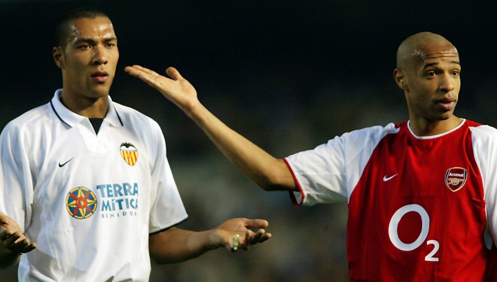Arsenal have an old score to settle in Valencia 3 VALENCIA - MARCH 19: Thierry Henry (right) of Arsenal with John Carew (left) of Valencia show they are the same colour to try to calm the fans down after Thierry Henry gets racial abuse from the home fans during the UEFA Champions League Second Phase Group B match held on March 19, 2003 at Mestalla Camp Del Valencia, in Valencia, Spain. Valencia won the match 2-1. (Photo by Ben Radford/Getty Images)