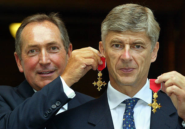 Gerard Houllier (L) of Liverpool holds his OBE medal as an earring on long-term friend and fellow manager Arsene Wenger of Arsenal, after being awa...