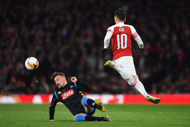 LONDON, ENGLAND - APRIL 11: Mario Rui of Napoli tackles Mesut Ozil of Arsenal during the UEFA Europa League Quarter Final First Leg match between A...