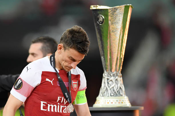 BAKU, AZERBAIJAN - MAY 29: Laurent Koscielny of Arsenal looks dejected as he walks past the Europa League Trophy whilst coduring the UEFA Europa League Final between Chelsea and Arsenal at Baku Olimpiya Stadionu on May 29, 2019 in Baku, Azerbaijan. (Photo by Michael Regan/Getty Images)