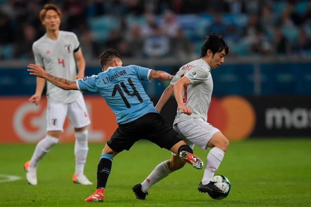 Japan's Shoya Nakajima(R) is challenged by Uruguay's Lucas Torreira during the Copa America football tournament Group C match at the Gremio Arena S...