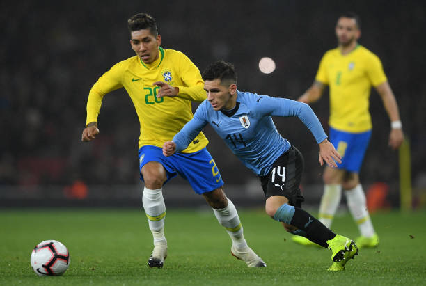 Lucas Torreira of Uruguay gets past Roberto Firmino Barbosa de Oliveira of Brazil during the International Friendly between Brazil and Uruguay at E...