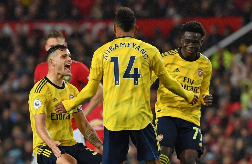 Arsenal's Gabonese striker Pierre-Emerick Aubameyang (C) celebrates with Arsenal's Swiss midfielder Granit Xhaka (L) and Arsenal's English striker Bukayo Saka (R) after scoring their first goal, decision of off-side overturned by VAR (Video Assistant referee) during the English Premier League football match between Manchester United and Arsenal at Old Trafford in Manchester, north west England, on September 30, 2019. (PAUL ELLIS / AFP / Getty Images)