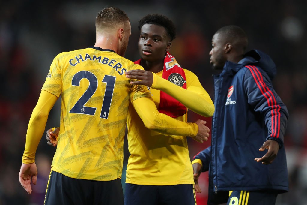 MANCHESTER, ENGLAND - SEPTEMBER 30: Bukayo Saka of Arsenal embraces Calum Chambers of Arsenal after the Premier League match between Manchester Uni...