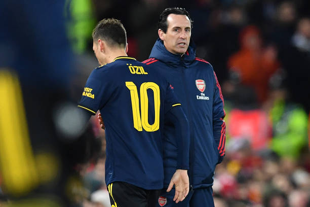 Arsenal's German midfielder Mesut Ozil (L) passes Arsenal's Spanish head coach Unai Emery as he leaves the pitch after being substituted off during the English League Cup fourth round football match between Liverpool and Arsenal at Anfield in Liverpool, north west England on October 30, 2019. (Photo by Paul ELLIS / AFP)