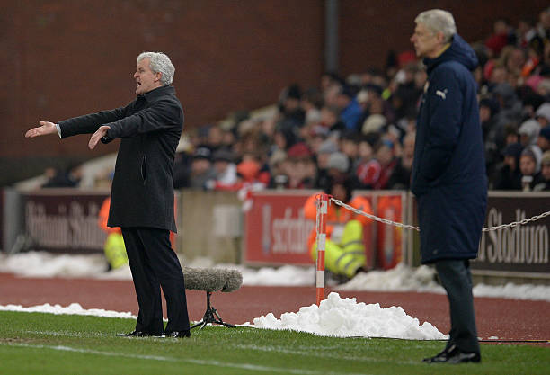 Arsenal's French manager Arsene Wenger (R) and Stoke City's Welsh manager Mark Hughes watch thier players during the English Premier League footbal...
