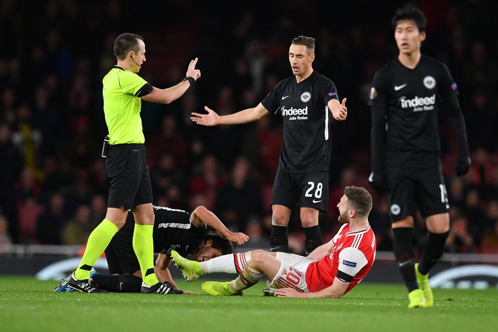 Frankfurt's German midfielder Dominik Kohr (C) reacts as Arsenal's German defender Shkodran Mustafi lies on the ground during their UEFA Europa lea...
