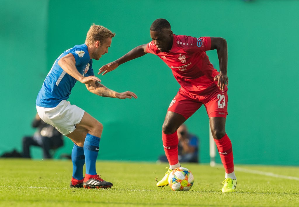 ROSTOCK, GERMANY - AUGUST 12: Orel Mangala of VfB Stuttgart is challenged by Nils Butzen of Hansa Rostock during the DFB Cup first round match betw...