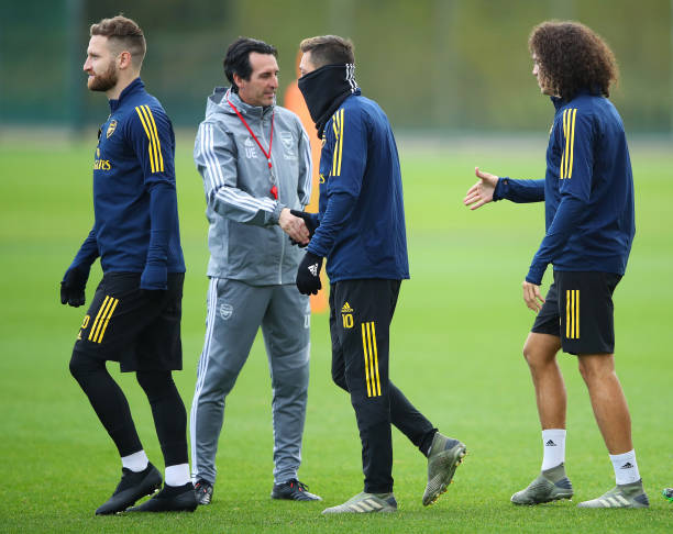 ST ALBANS, ENGLAND - NOVEMBER 27:  Unai Emery, Manager of Arsenal shakes hands with Mesut Ozil and team mates Shkodran Mustafi and Matteo Guendouzi during an Arsenal training session on the eve of their UEFA Europa League match against Eintracht Frankfurt at London Colney on November 27, 2019 in St Albans, England. (Photo by Warren Little/Getty Images)