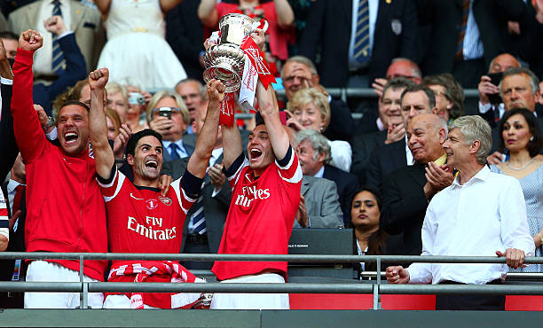 Arsenal fan favourite explains turning down Manchester City 2 LONDON, ENGLAND - MAY 17: Captain Thomas Vermaelen of Arsenal (2R) lifts the trophy in celebration alongside Lukas Podolski (L), Mikel Arteta (2L) and Arsene Wenger manager of Arsenal (R) after the FA Cup with Budweiser Final match between Arsenal and Hull City at Wembley Stadium on May 17, 2014 in London, England. (Photo by Clive Mason/Getty Images)
