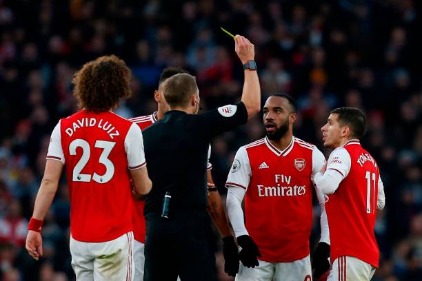 Arsenal's French striker Alexandre Lacazette (2R) is shown a yellow card by referee Craig Pawson during the English Premier League football match b...