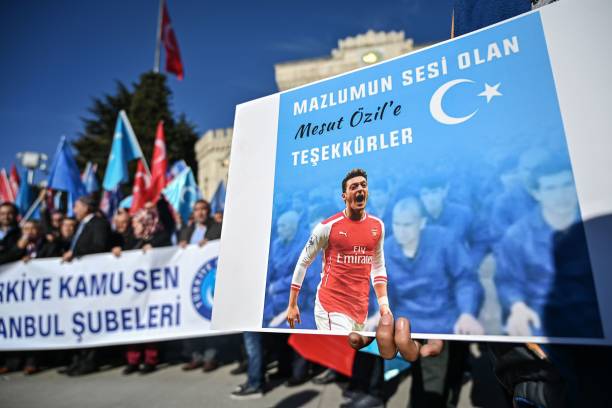 A supporter of China's Muslim Uighur minority holds a placard of Arsenal's Turkish origin German midfielder Mesut Ozil reading "Thanks for being ou...