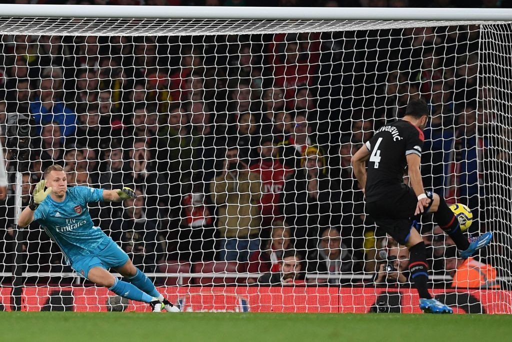 Crystal Palace's Serbian midfielder Luka Milivojevic (R) scores their first goal past Arsenal's German goalkeeper Bernd Leno (L) from the penalty s...