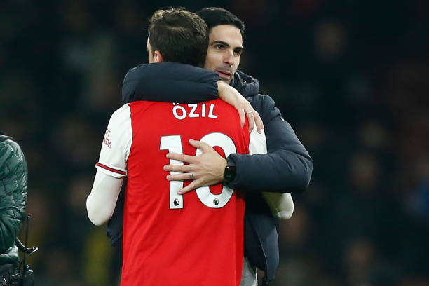 Arsenal's Spanish head coach Mikel Arteta (R) embraces Arsenal's German midfielder Mesut Ozil (L) on the pitch after the English Premier League foo...