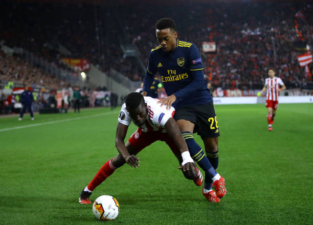 Ousseynou Ba of Olympiacos FC battles for possession with Joe Willock of Arsenal during the UEFA Europa League round of 32 first leg match between ...