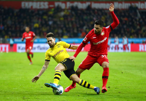 Raphael Guerreiro of Borussia Dortmund battles for the ball with Kevin Volland of Bayer 04 Leverkusen during the Bundesliga match between Bayer 04 Leverkusen and Borussia Dortmund at BayArena on February 08, 2020 in Leverkusen, Germany. 
