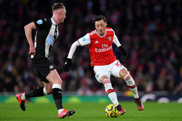 Mesut Ozil of Arsenal takes on Sean Longstaff of Newcastle United during the Premier League match between Arsenal FC and Newcastle United at Emirates Stadium on February 16, 2020 in London, United Kingdom.