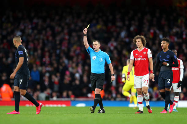 Referee Stuart Attwell shows Richarlison of Everton a yellow card during the Premier League match between Arsenal FC and Everton FC at Emirates Stadium on February 23, 2020 in London, United Kingdom.