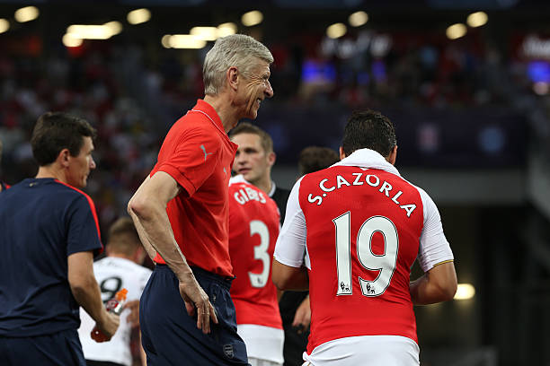 SINGAPORE - JULY 18: Arsene Wenger of Arsenal smiles at Santi Cazorla of Arsenal during the Barclays Asia Trophy match between Arsenal and Everton at the National Stadium on July 18, 2015 in Singapore. (Photo by Lionel Ng/Getty Images)