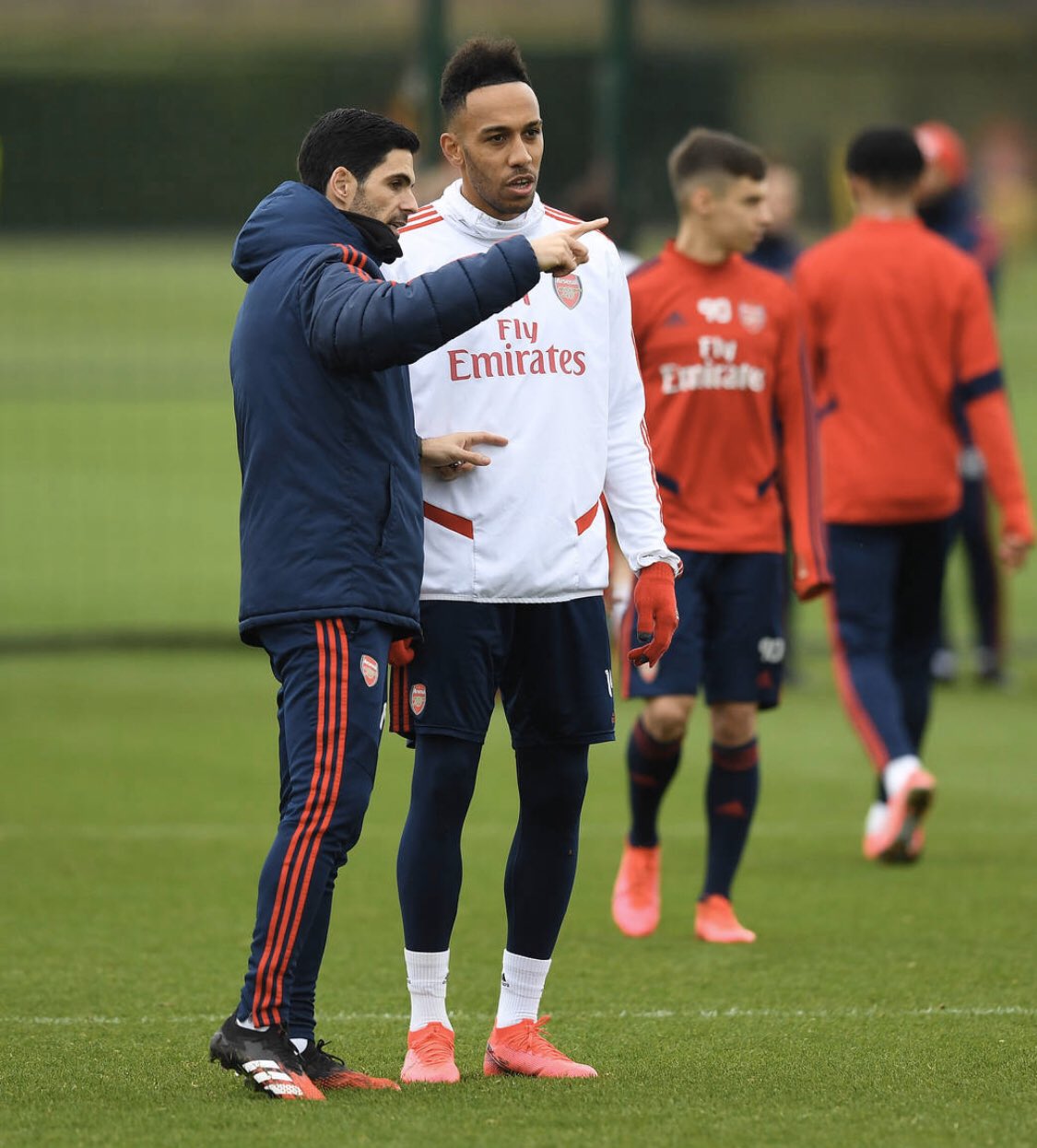Mikel Arteta and Pierre-Emerick Aubameyang speak in the foreground, with Catalin Cirjan behind them. Triallist Tyger Smalls walks away in the background (Photo via Tyger Smalls on Twitter)