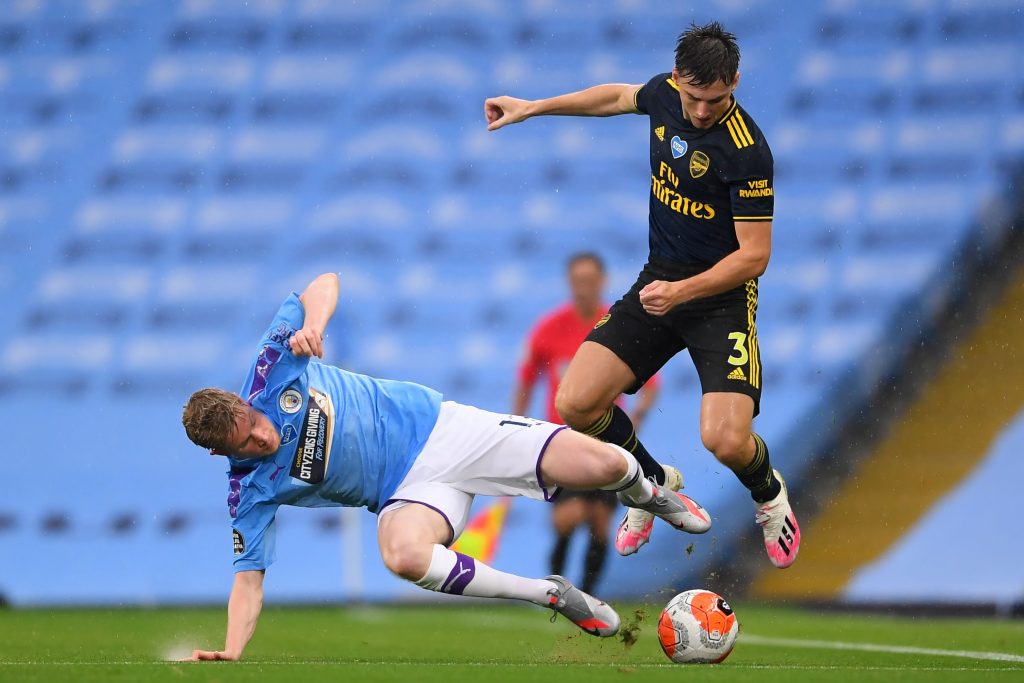 Manchester City's Belgian midfielder Kevin De Bruyne (L) tackles Arsenal's Scottish defender Kieran Tierney during the English Premier League football match between Manchester City and Arsenal at the Etihad Stadium in Manchester, north west England, on June 17, 2020. - The Premier League makes its eagerly anticipated return today after 100 days in lockdown but behind closed doors due to coronavirus restrictions. (Photo by LAURENCE GRIFFITHS / POOL / AFP) / RESTRICTED TO EDITORIAL USE. No use with unauthorized audio, video, data, fixture lists, club/league logos or 'live' services. Online in-match use limited to 120 images. An additional 40 images may be used in extra time. No video emulation. Social media in-match use limited to 120 images. An additional 40 images may be used in extra time. No use in betting publications, games or single club/league/player publications. / (Photo by LAURENCE GRIFFITHS/POOL/AFP via Getty Images)